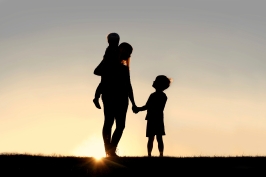 Silhouette of Mother and Young Children Holding Hands at Sunset